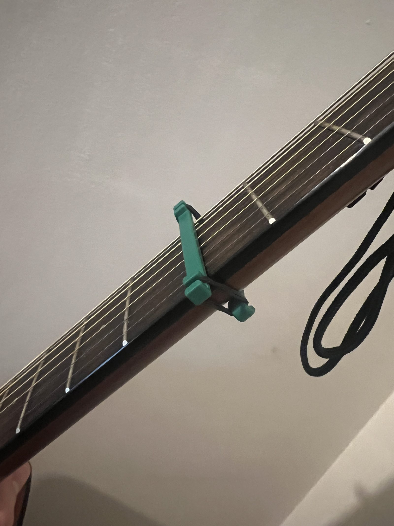 First capo prototype, a flat bar held with rubber bands, mounted on a guitar neck